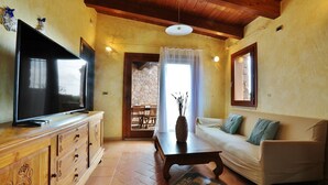 A cozy living room with a television, sofa, and wooden cabinet.