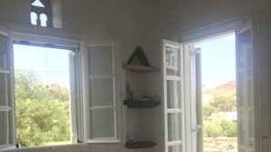 Ein Schlafzimmer mit einem Bett, einem Fenster und einer Tür, die zu einem Außenbereich führt.