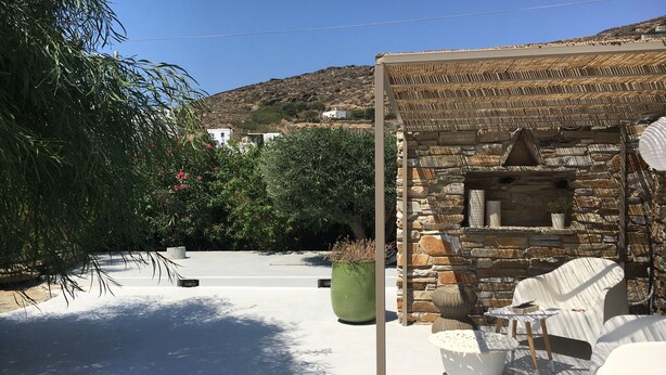 Eine Terrasse mit Steinmauern, einer Pergola und Gartenmöbeln.