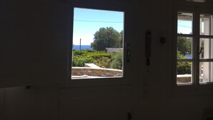 Ein Zimmer mit großem Fenster und Blick auf Grünflächen sowie ein Gebäude in der Ferne.