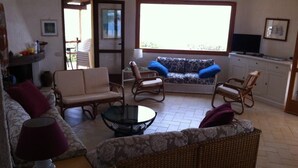 Un salon comprenant un canapé, des fauteuils, une table basse et un téléviseur.