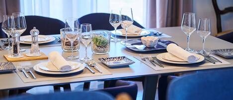 A dining table set with plates, glasses, cutlery, and a small plant.
