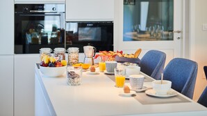 A breakfast table with various food items and drinks, a coffee maker, and a television in the background. - New Property with Heated Pool near Bike Trails and Truffle Capital of Istria (Oprtalj)