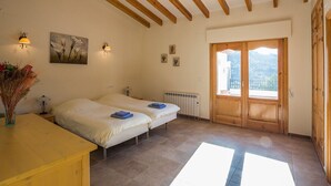 Una habitación con dos camas, techo de madera, radiador y un ventanal con vistas al exterior.