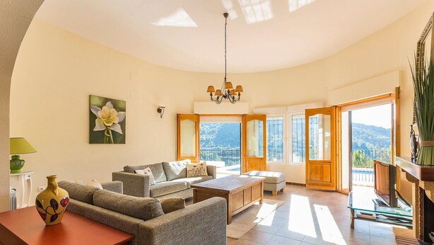 Amplia sala de estar con un juego de sofá, una mesa de centro de madera y vistas al exterior a través de ventanas grandes.