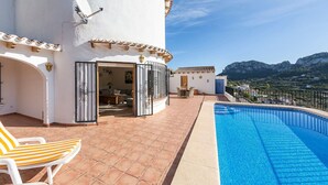 Una villa con piscina, mobiliario de exterior y vistas a las montañas.