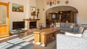 Una sala de estar con chimenea, televisor, sofá y comedor con sillas y mesa.