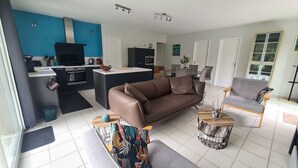 Un salon moderne avec un canapé marron, un fauteuil gris et une table basse agrémentée d’un vase décoratif.