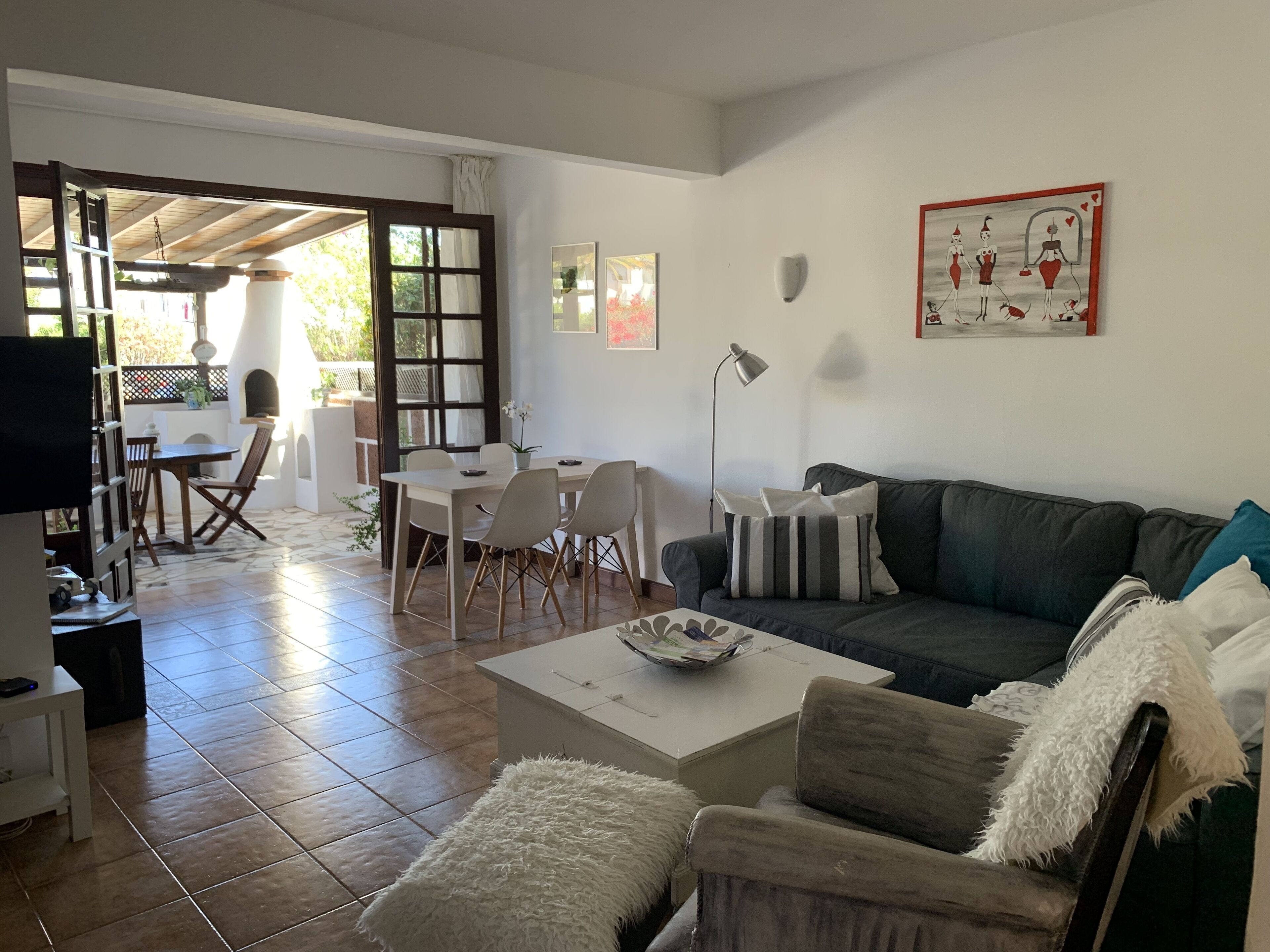 A living room with a sofa, a coffee table, a dining table with chairs, a TV, and a fireplace.
