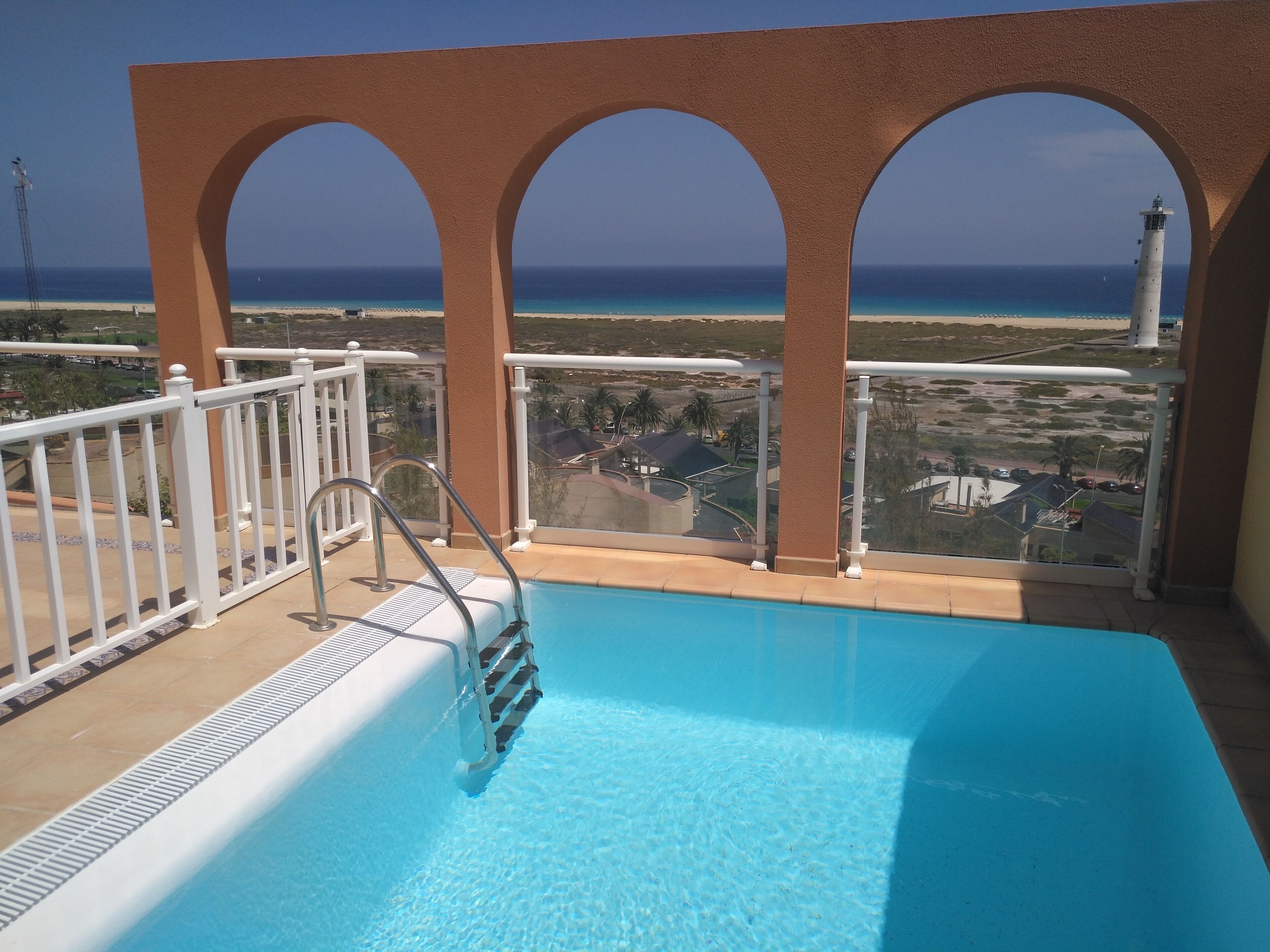 Una piscina con vista sull'oceano e un faro in lontananza.