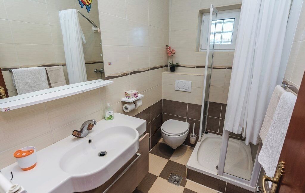 A bathroom with two sinks, a toilet, a shower, and a window.