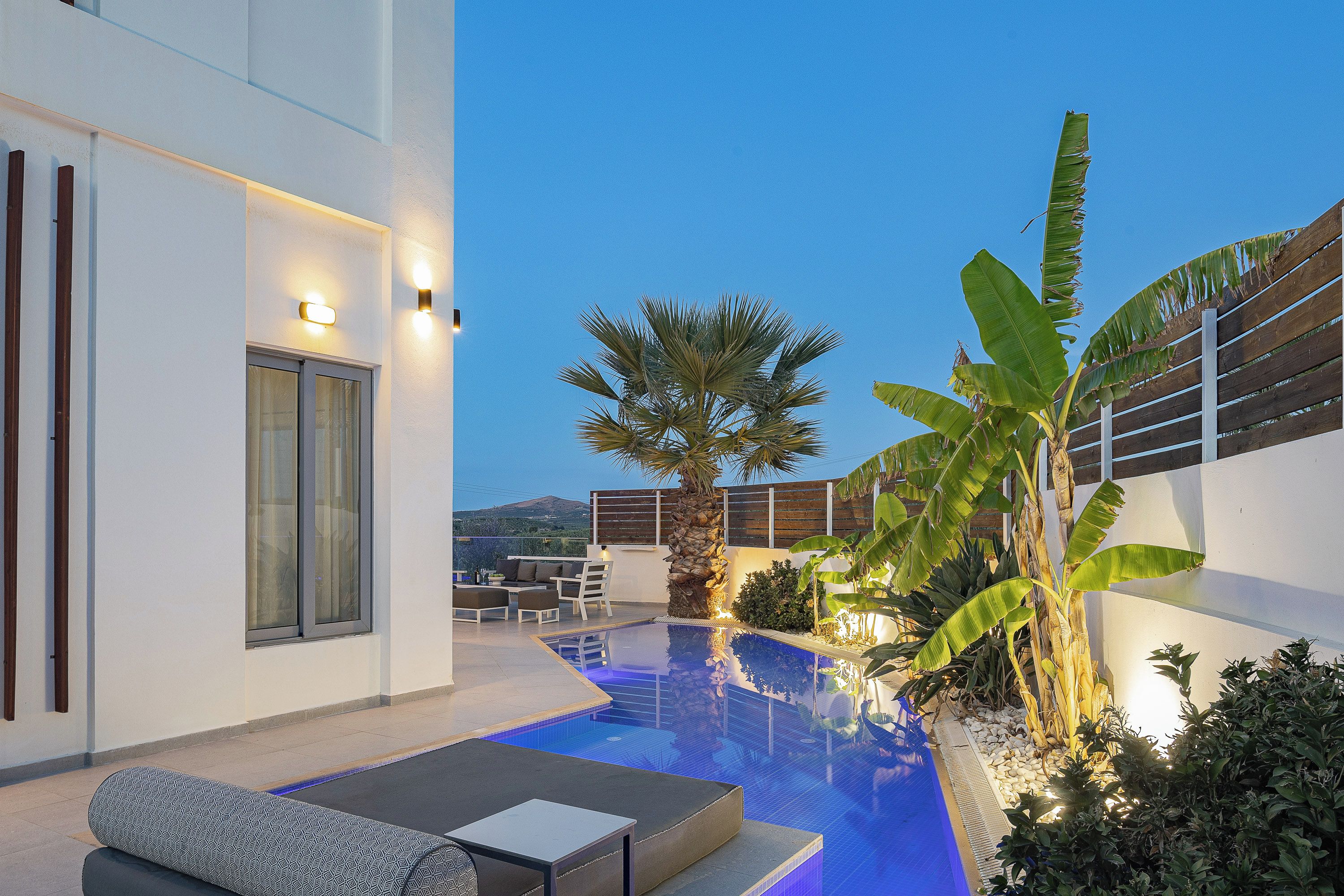 A modern outdoor pool area with a lounge, seating, and a view of the landscape.