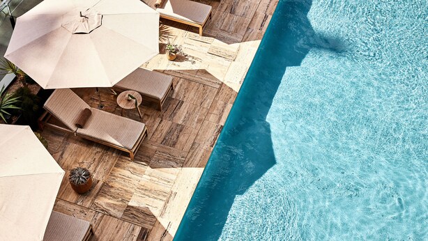 Un espace piscine aménagé sur le toit, avec des chaises longues et des parasols.