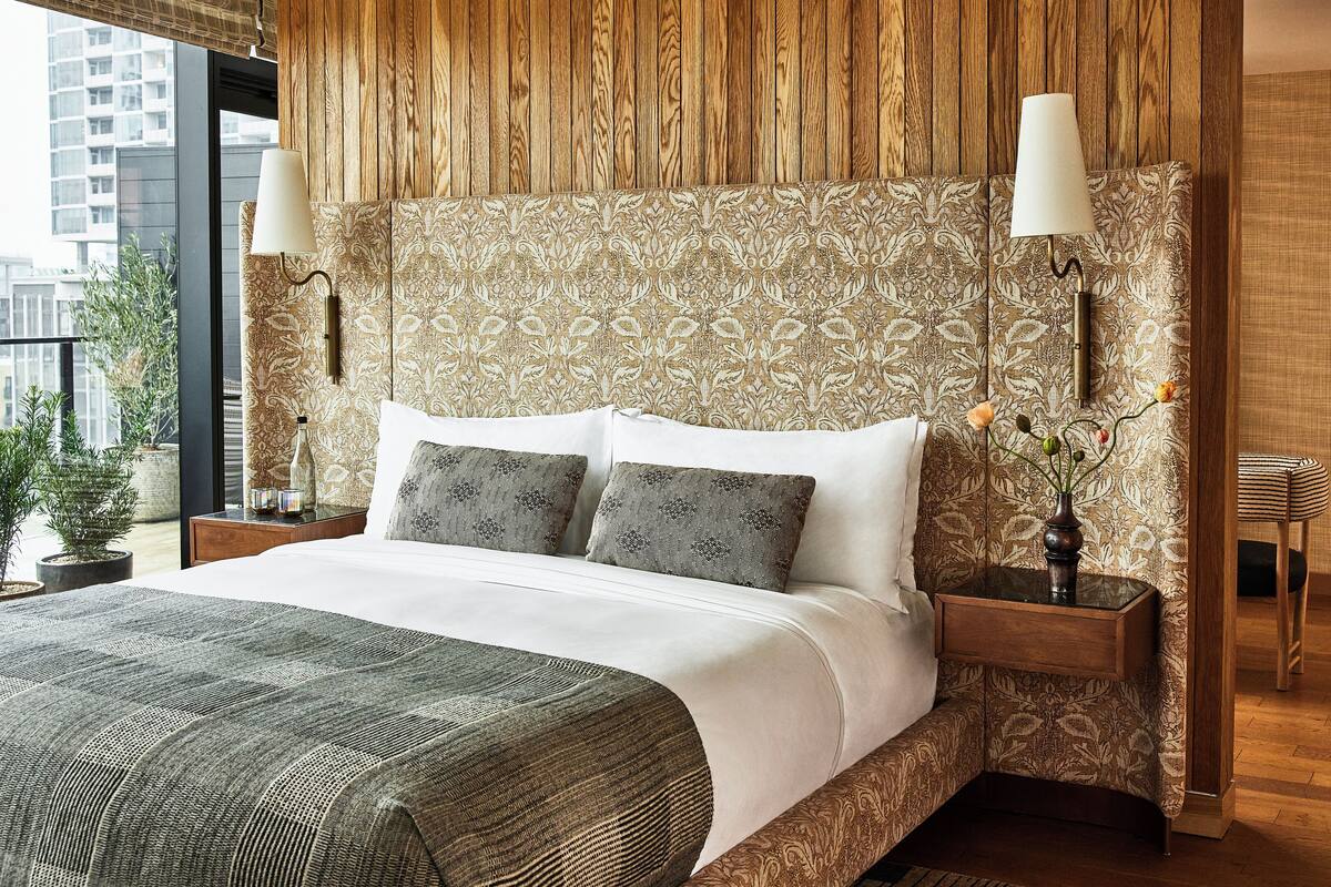 A modern bedroom with a large bed, patterned wallpaper, and a view of the city.