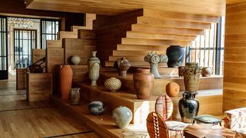 Una escalera de madera con varios jarrones y una zona de estar con sillas y mesas.