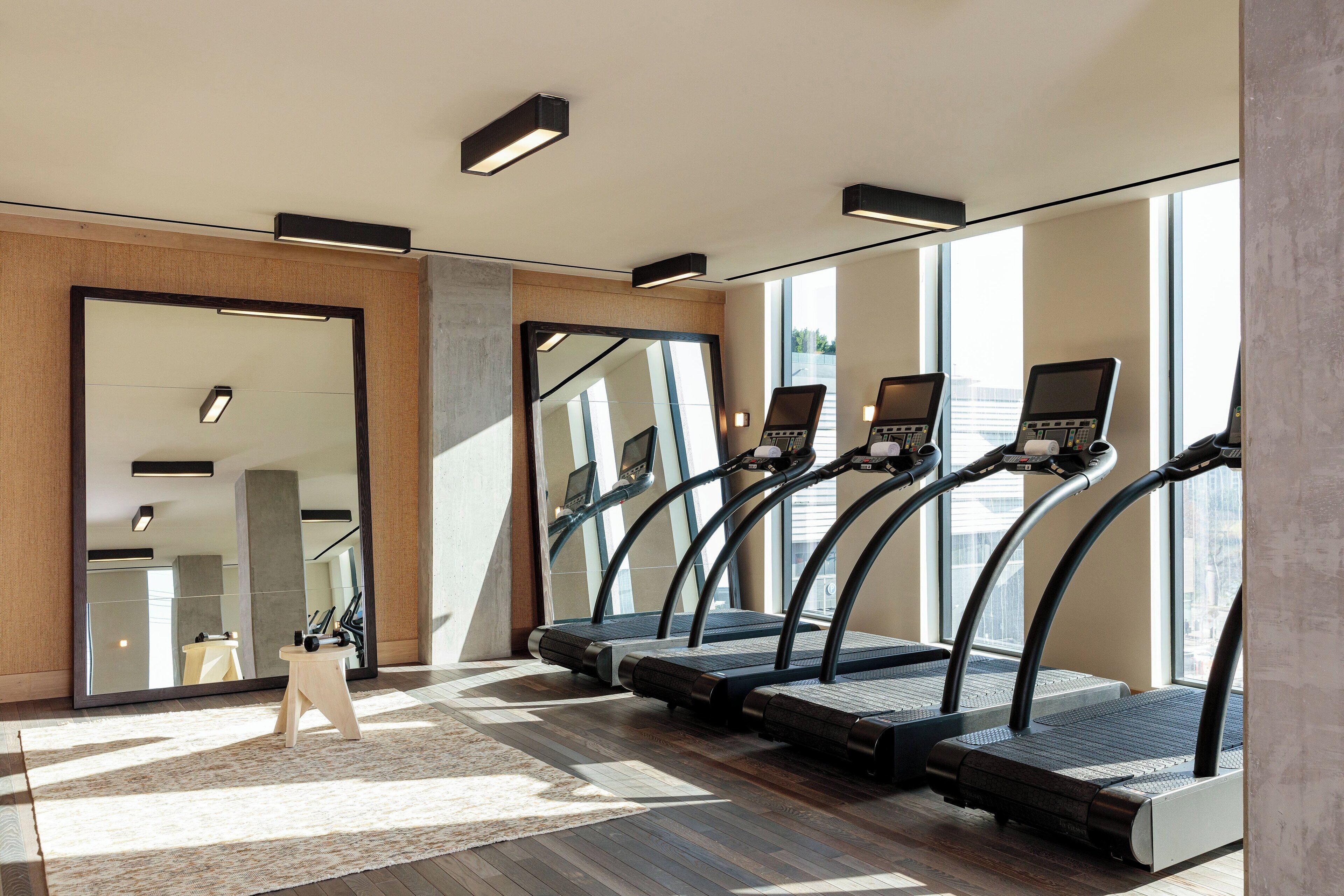 A gym with treadmills, a mirror, and a wooden stool.