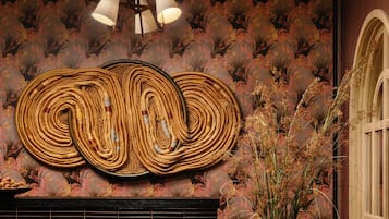 Un mur orné d’un motif tissé, un luminaire suspendu au plafond et une fenêtre offrant une vue.