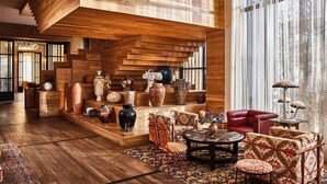 Une pièce spacieuse avec un escalier en bois, un canapé en cuir rouge et divers objets de décoration.