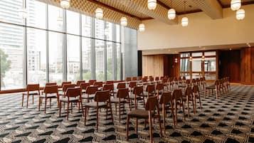 A conference room with rows of chairs, large windows, and patterned carpet.