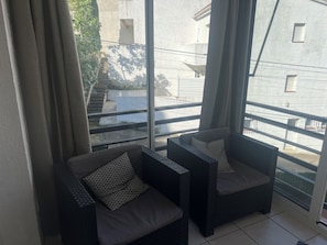 Een balkon met twee stoelen en uitzicht op een gebouw en trap.