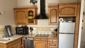 Une cuisine compacte avec des meubles en bois, un four encastré, un lave-vaisselle et un réfrigérateur.
