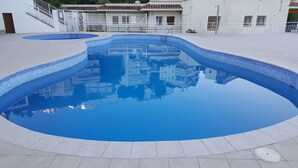 Une piscine dont le bord est recouvert de carreaux et qui reflète les bâtiments environnants.