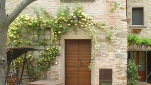 A stone building with a wooden door, a small table, and a bench. - Awesome 1BR Countryside Tower Suite w shared pool & gorgeous gardens (Cortona)
