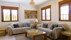 Ein Wohnzimmer mit zwei Sofas, einem Glastisch, einer Lampe und einer Weltkarte an der Wand.