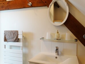 Een badkamer met een witte wastafel, een spiegel en een handdoek aan een rek.