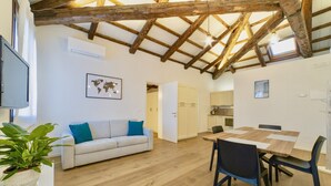 A cozy room with a wooden ceiling, a sofa with blue cushions, a dining table with chairs, and a world map on the wall. - New apartment in Murano the amazing glass island (Venezia)