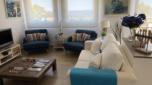 Ein Wohnzimmer mit zwei Sofas, einem Couchtisch, einem Fernseher und Kunstwerken an den Wänden.