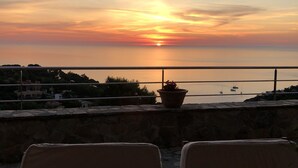 Ein Sonnenuntergangsblick von einer Terrasse mit zwei Stühlen und einem Blumentopf.