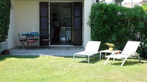 A patio with two white lounge chairs, a small table, and a folding table with chairs. - Apartment in residence with private garden and swimming pool for adults and children and tennis (Lazise)