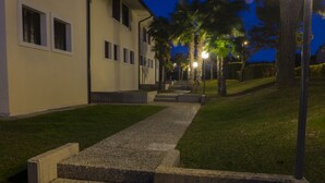 A pathway leading to a building with a modern design, featuring a series of steps and a well-maintained lawn. - Apartment in residence with private garden and swimming pool for adults and children and tennis (Lazise)