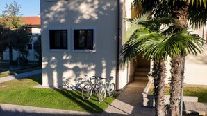 A building with a white exterior, two windows, and a bicycle parked in front. - Apartment in residence with private garden and swimming pool for adults and children and tennis (Lazise)