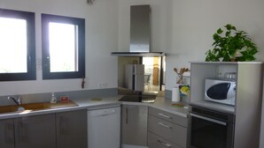 A modern kitchen with a dishwasher, microwave, oven, and a plant on the counter. - Fully air-conditioned stone villa with panoramic views and private pool. (Labeaume)