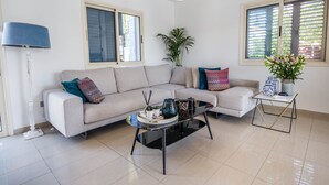 A modern living room with a sofa, coffee table, and decorative items. - Nirvana Seaside Villa (Pervolia)