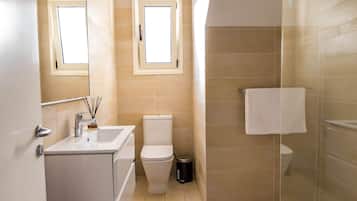 Un baño moderno con cabina de ducha de vidrio, inodoro y lavamanos con espejo.