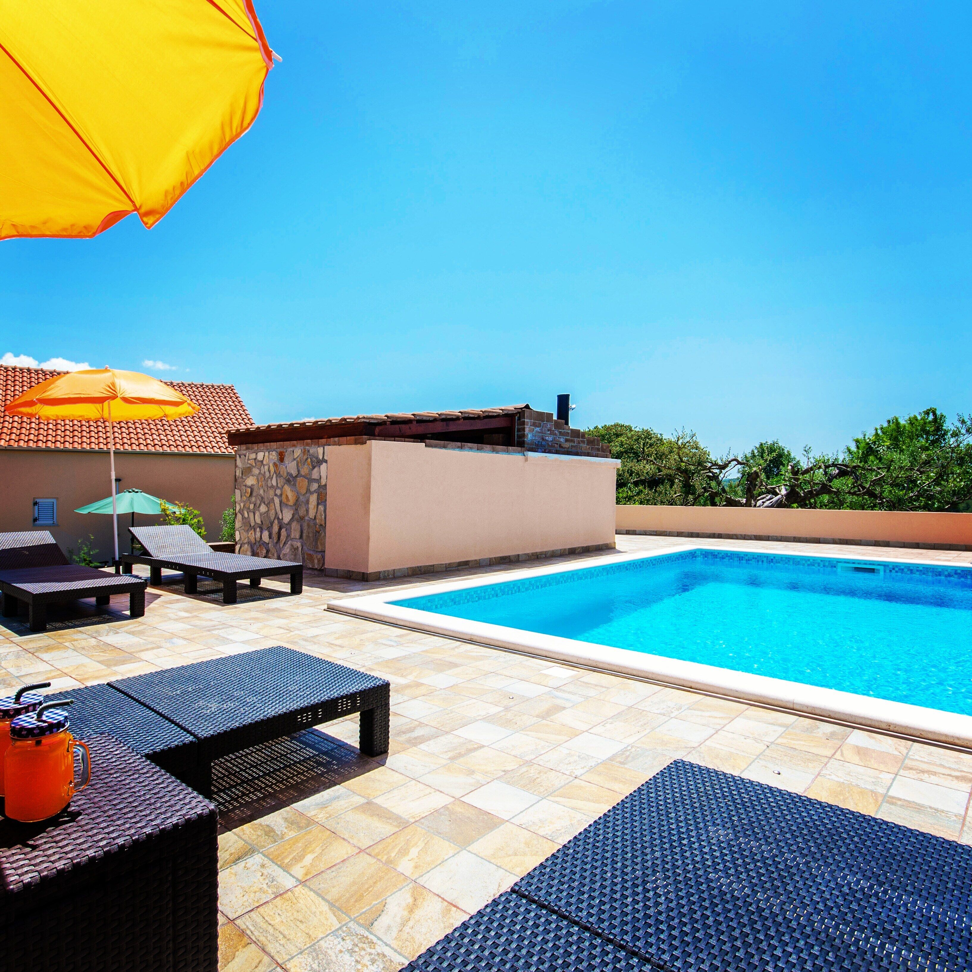 A swimming pool with lounge chairs and a stone wall.
