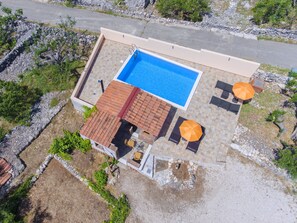 An aerial view of a property with a swimming pool, outdoor seating, and a patio area.
