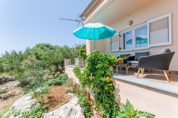 A patio area with outdoor furniture, a stone wall, and a view of the surrounding landscape.