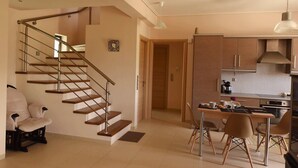 Une cuisine moderne avec des meubles en bois, un coin repas comprenant une table et des chaises, et un escalier menant à un autre niveau.