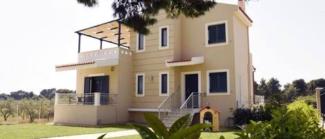 A two-story building with a balcony, a small doghouse, and a staircase leading to the entrance.