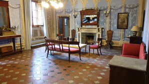 Quarto com um banco de madeira, uma poltrona vermelha, lareira e piso estampado.