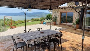 Une terrasse extérieure avec une table et des chaises, une pergola et une vue sur un lac et des montagnes.