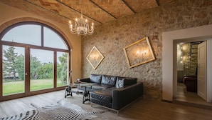 Un salon spacieux avec une grande fenêtre, un canapé en cuir, un tapis à motifs zébrés et un lustre.