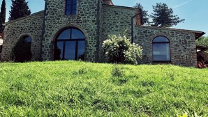 Un bâtiment en pierre doté de deux fenêtres en arc de cercle et d’une petite tour.