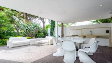 Eine moderne Außenpatio mit weißer Möbel, einem Esstisch und einer Küchenzeile.