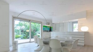 A modern dining area with a round table and white chairs, large windows with a view of greenery, and a minimalist design. - Beautiful beach with Private Pool Villa in Castellammare del Golfo (Castellammare del Golfo)