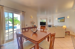 A spacious living room with a dining area, a flat-screen TV, and a fireplace.